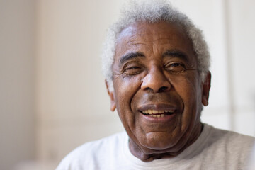 Close-up of elderly mans face. Happy African American man with grey and curly hair smiling and...