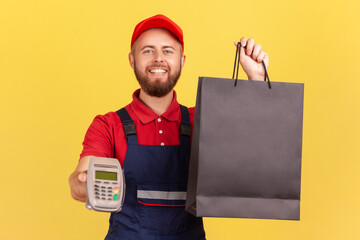 Portrait of bearded happy positive courier man bringing order in black shopping bag and giving pos...