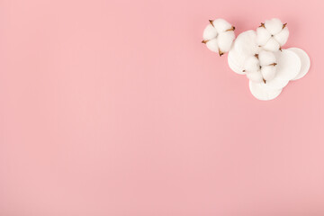 Cotton pads and cotton flowers on a pink background.