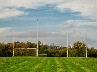 Training pitch for Irish National sport camogie, hurling, rugby and Gaelic football with tall goal posts and freshly cut grass. Nobody. Cloudy sky. Popular activity.