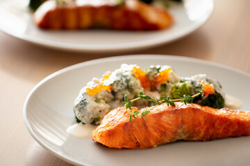 Salmon steak with broccoli on a white plate.