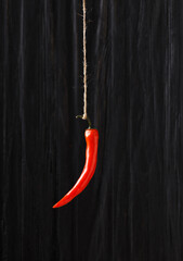 Red chili pepper hanging against a dark wooden background. Close-up