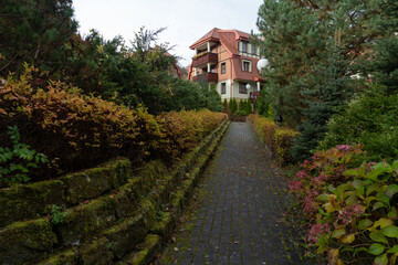 cobblestone path leading to the building along an old stone wall overgrown with moss close-up in autumn