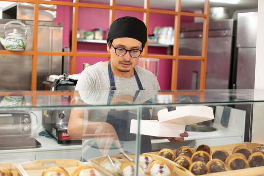 Baker serving croissants in a food box