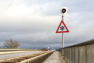 A sign on a traffic bridge in germany warning of frost and snow in late autumn