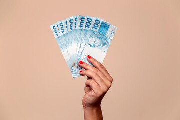 one hundred reais banknotes - hand holding brazilian banknotes