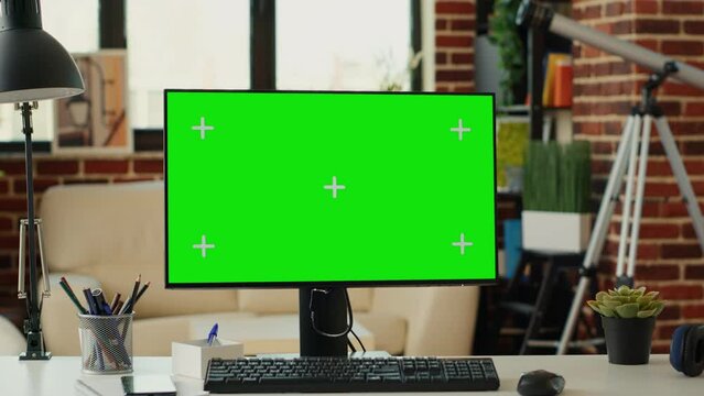 Empty desk with computer and greenscreen on monitor, showing chroma key display and isolated mockup template. Desktop pc screen with blank copy space background in living room.