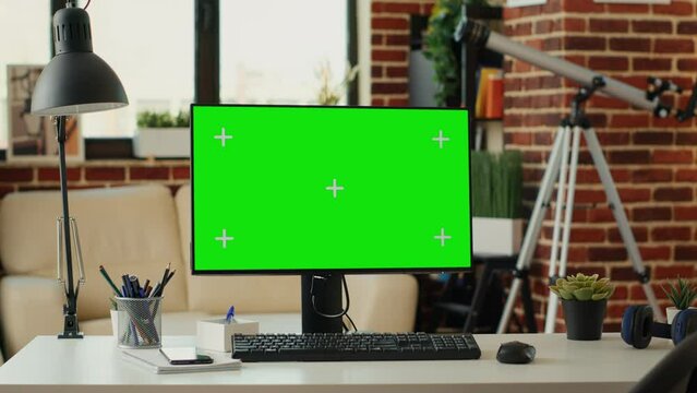 Greenscreen display on monitor with empty table in living room, workspace with chroma key blank background. Showing isolated copyspace with mokcup template on desktop computer at home.