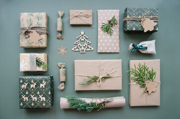 Eco friendly Christmas composition with gift boxes in craft reusable paper and natural decor on blue green background top view. Zero waste environmentally friendly Christmas concept.