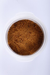 Top shot of muscovado sugar in a white bowl against a white background