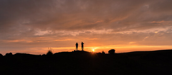 Couple looking at the horizon, silhouette of a beautiful sunset
