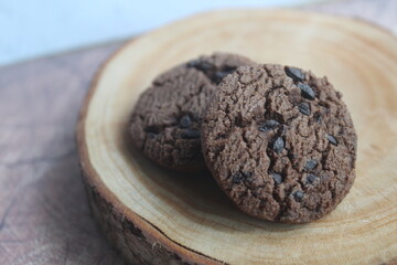 chocolate cookies sprinkled with chocolate chips, on a wooden slices
