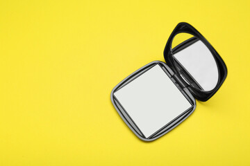 Stylish cosmetic pocket mirror on yellow background, top view. Space for text