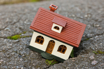 Obraz na płótnie Canvas House model in cracked asphalt. Earthquake disaster