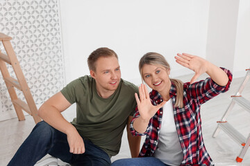 Young happy couple discussing interior details in apartment during repair