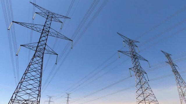 Several large electrical towers and power lines against blue sky, pan right; in Ontario, Canada.
