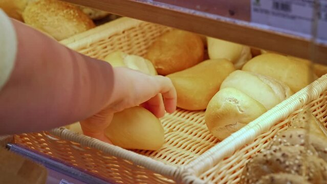 Caucasian Female Picking Bread Rolls From Backet at Grocery Store Bakery Stand