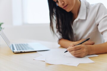 A woman works and learns by writing down text on paper with a pen and checking for errors, studying and teaching in college, business work