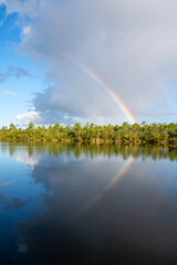 Rainbow and clouds over Pine Glades Lake in Everglades National Park, Florida on sunny autumn morning.