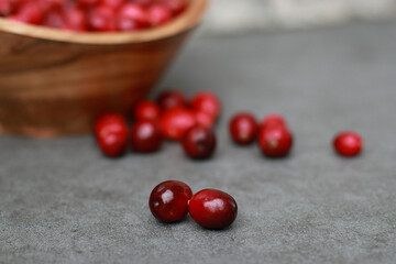 close up of fresh cranberries in a wooden bowl, grey marble table 