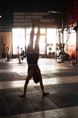 young caucasian sporty woman doing crossfit alone in a large gym doing a handstand