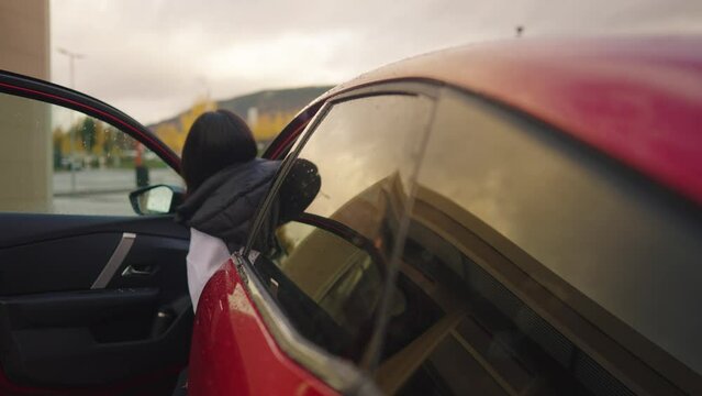 Woman sitting in an electirc vehicle by charging station