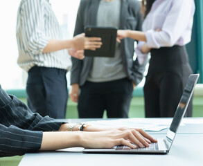 close up hand of businesswoman working with latptop. group of man and woman standing and working with tablet together at background.