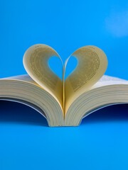 Book page in the shape of a heart on a blue background