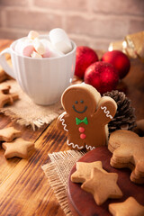 Christmas Homemade gingerbread man cookie and white cup with hot chocolate with marshmallows, traditionally made at wintertime and the holidays.