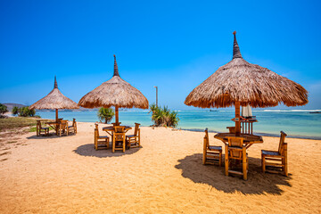 Fototapeta na wymiar Beautiful tropical beach in kuta Lombok with wooden chair and sunbeds/ umbrella