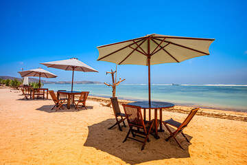 Beautiful tropical beach in kuta Lombok with wooden chair and sunbeds/ umbrella