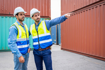 Two male engineers in a container shipping company Consulting to check the order for the container that is responsible	
