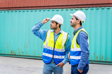 Two male engineers in a container shipping company Consulting to check the order for the container that is responsible	

