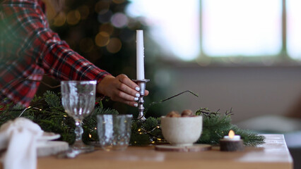 Festive table on which female hands put candle. Christmas family dinner, family puts food on table. Christmas theme