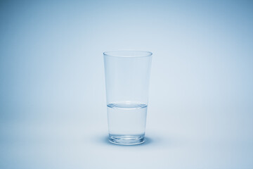 Half a glass of water with blue background.