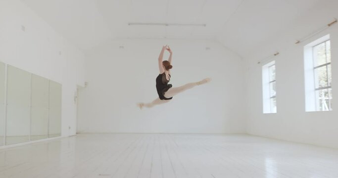 Ballerina, ballet dancer and split jumping performance, training rehearsal and choreography with split jumping technique in dance studio. Graceful, elegant and creative woman dancing skill practice