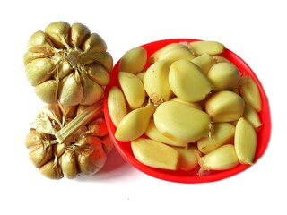 Garlic cloves and fresh garlic in a red bowl on a white background. Popular seasoning for the kitchen