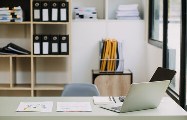 Young business woman sitting in office at table and using smartphone. On desk is laptop and tablet computer, on screen charts and graphs. Woman analyzing data. Student learning online.