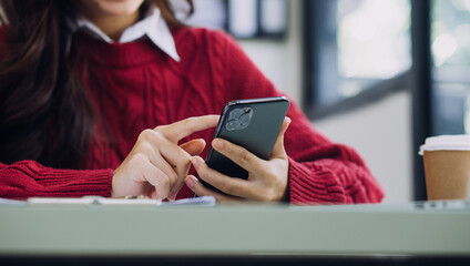 Young business woman sitting in office at table and using smartphone. On desk is laptop and tablet computer, on screen charts and graphs. Woman analyzing data. Student learning online.