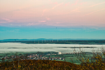 Obraz premium Panorama-Ausblick vom Aussichtsturm auf der Berggipfel Zabelstein bei Hundelshausen im Steigerwald, Blick über das Maintal nach Schweinfurt und Gerolzhofen bei Sonnenaufgang und Nebelschwaden