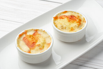 Baked julienne with mushrooms and cheese on top on white plate
