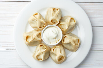 Russian meat dumplings with sour cream on white plate