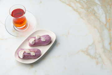 Two eclair cakes with violet frosting on white plate