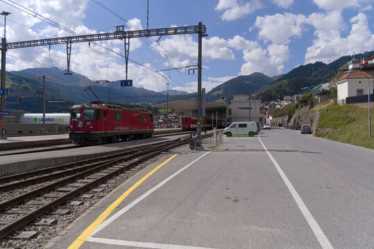 Red RHB locomotive named Domat Ems at railway station of Disentis Mustér on a sunny late summer day. Photo taken September 5th, 2022, Disentis, Switzerland.