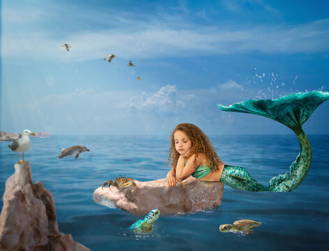Girl mermaid with green tail lying on ocean rock visits with turtle friends