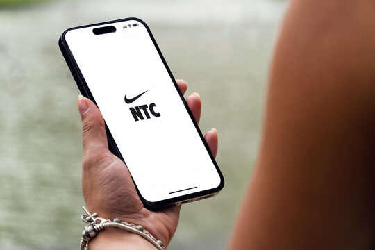 Girl in the park holding a smartphone iPhone 14 Pro with Nike Training Club NTC app on the screen. Lake in the background. Rio de Janeiro, RJ, Brazil. November 2022