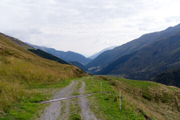 Fototapeta na wymiar Hiking trail with scenic landscape at region Oberalppass Surselva on a blue cloudy late summer day. Photo taken September 5th, 2022, Oberalp Pass, Switzerland.
