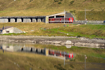Beautiful landscape at Oberalppass with lake and reflections of MGB train and mountain panorama on...