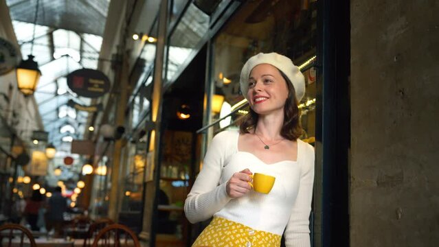 Attractive tourist with a yellow cup of coffee in a Parisian gallery
