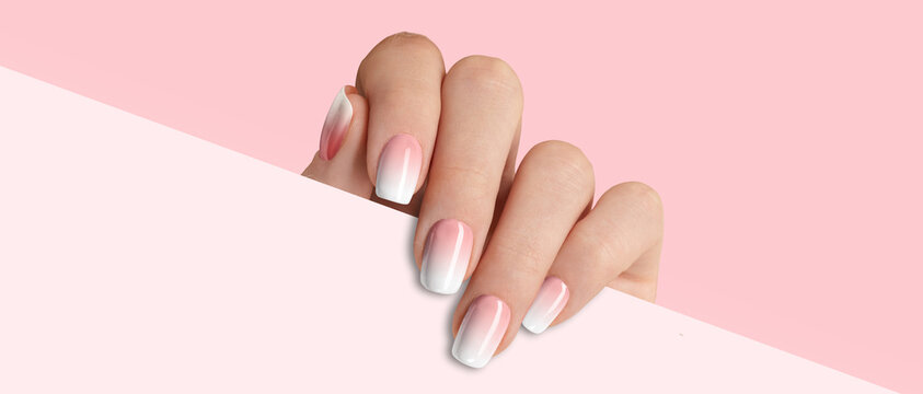 Manicured woman's hand holding white paper. Fashionable pink nail design
